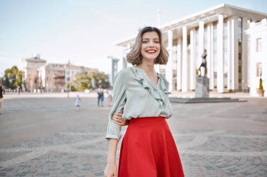 Sokakta yürüyen kırmızı etekli neşeli sarışın.