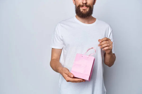 Un homme en t-shirt blanc tenant un cadeau cadeau cadeau rose — Photo