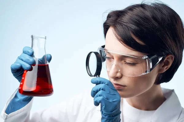 Assistente de laboratório feminino olha através de uma lupa em um processo de pesquisa bioquímica — Fotografia de Stock