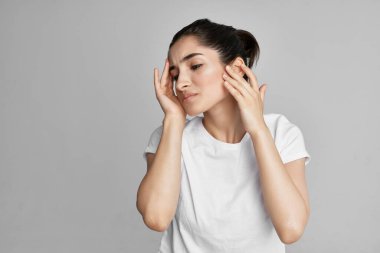 Beyaz tişörtlü kadın yüz tatminsizliği sorunu yaşıyor.