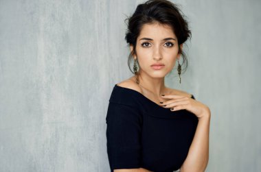 Siyah elbiseli kadın küpelerini takıyor.