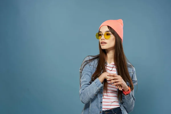 Mooie vrouw dragen bril moderne kleding denim jas blauwe achtergrond — Stockfoto