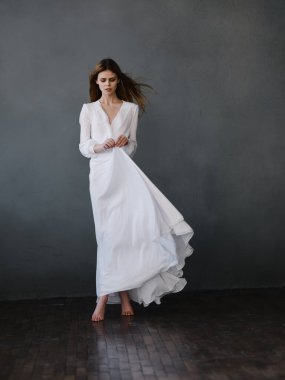 Beyaz elbiseli kadın cazibe stüdyosunda poz veriyor.