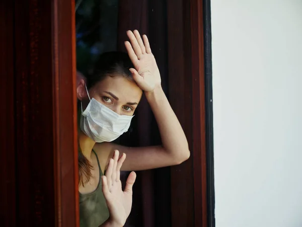 Mujer cogida de la mano en la ventana usando la máscara médica de bloqueo — Foto de Stock