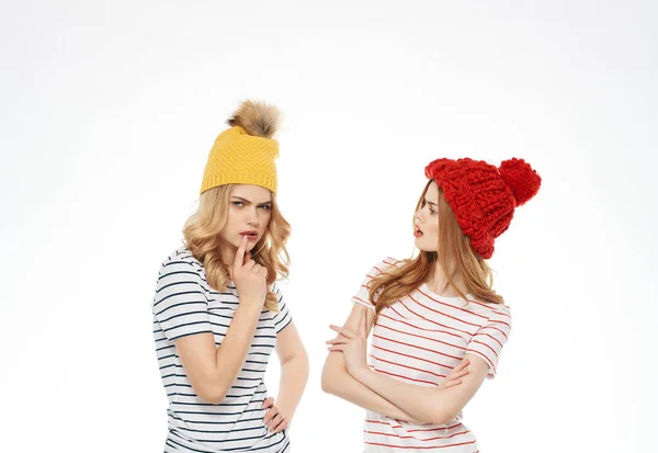 Δύο φίλες με πολύχρωμα καπέλα στέκονται δίπλα-δίπλα μοντέρνο φως της μόδας φόντο — Φωτογραφία Αρχείου