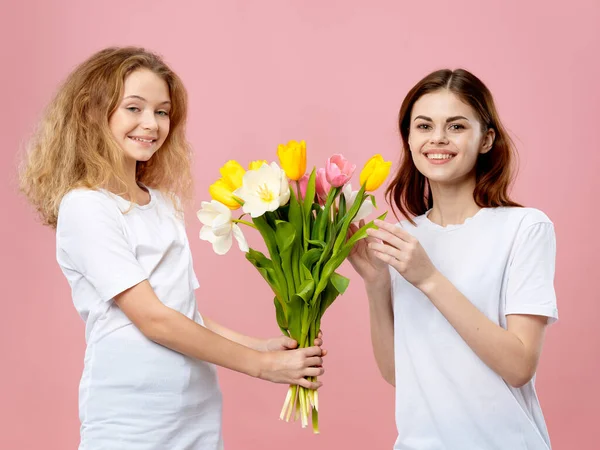 Bonito mãe e filha com um buquê de flores férias fundo rosa — Fotografia de Stock