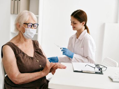 Hemşire yaşlı bir kadına pasaport aşısı yapıyor. Covid-19.