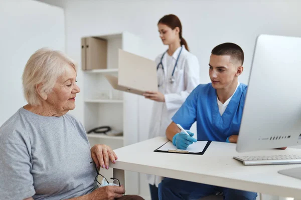 Un paciente en un médico y un profesional de enfermería cita diagnósticos de salud —  Fotos de Stock