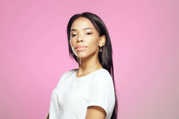 Mujer de aspecto africano en camiseta blanca peinado de moda posando fondo rosa — Foto de Stock