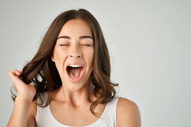 Ağzı açık, saçları beyaz tişörtlü duygusal bir kadın.