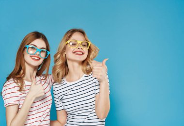 Gözlüklü iki neşeli kız arkadaş yaz moda arkadaşlığı mavi arka plan