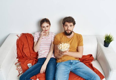 Patlamış mısırlı genç bir çift kanepede oturmuş film seyrediyor.