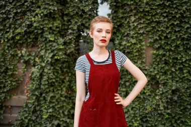 Arka planda çalıların üzerinde kısa saçlı güzel bir kadın