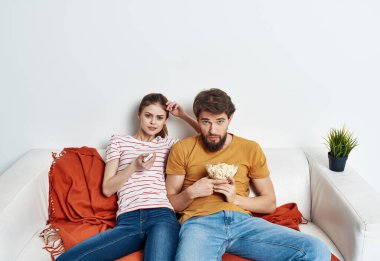 Patlamış mısırlı genç bir çift kanepede oturmuş film seyrediyor.