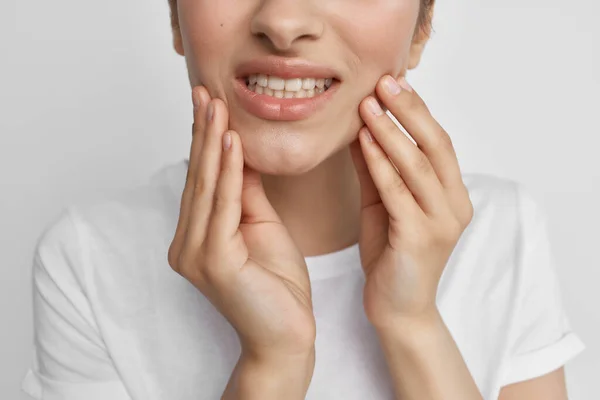 Mujer en camiseta blanca sosteniendo dolor de cara en los dientes problemas de salud odontología — Foto de Stock