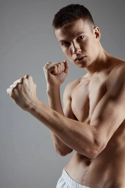 Portrét boxera se svalnatým tělem na šedém pozadí ruce v pěsti — Stock fotografie