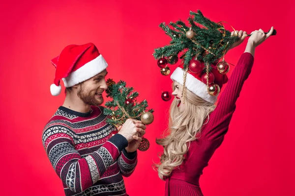 Joyeux jeune couple dans la nouvelle année vêtements décoration jouets fond rouge — Photo