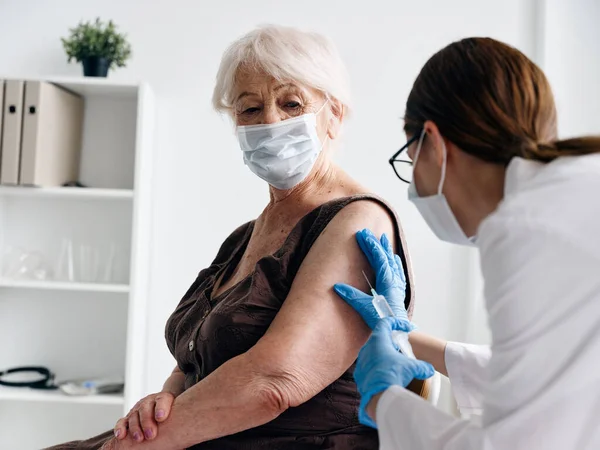 Sjuksköterska injicerar en äldre kvinna med vaccin pass coronavirus epidemi — Stockfoto