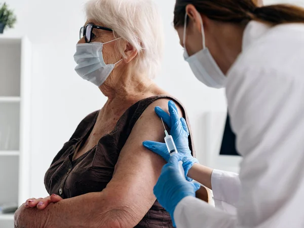 Sjuksköterska som ger en injektion till ett äldre kvinnas vaccinpass — Stockfoto