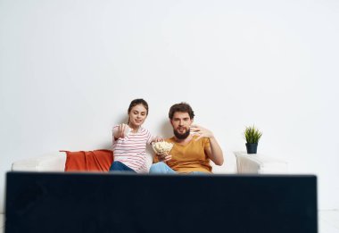 Kadın ve erkek kanepede film izleyip eğleniyorlar.