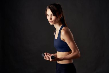 Elinde dambıllar olan spor kadını spor antrenmanı koyu arkaplan