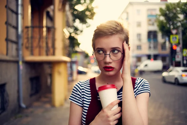 Femme aux cheveux courts portant des lunettes à l'extérieur marcher tasse de boisson de loisirs — Photo