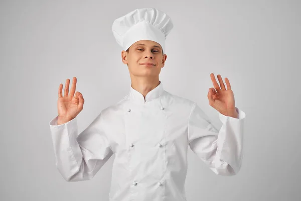 Un uomo in uniforme da chef che fa gesti con una mano che lavora in un ristorante professionista — Foto Stock