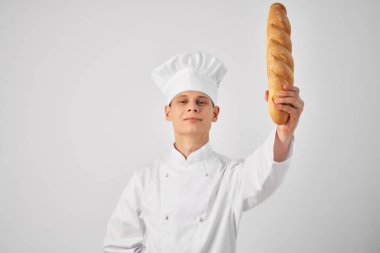 Aşçı kıyafetleri içindeki bir adam, bir fırıncının elinde bir somun ekmek ile.