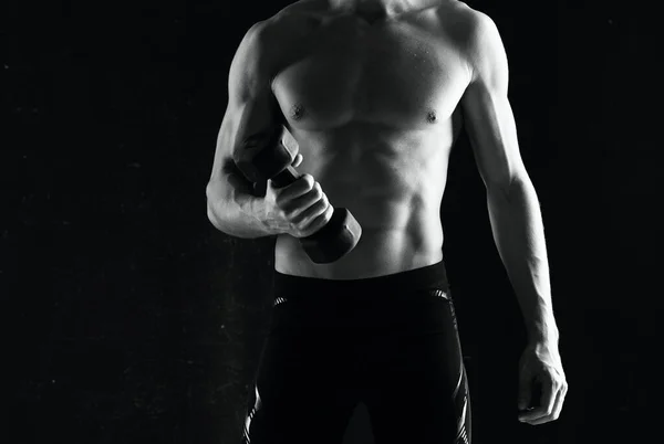 Sportieve man met halters in handen oppompen spieren oefeningen donkere achtergrond — Stockfoto