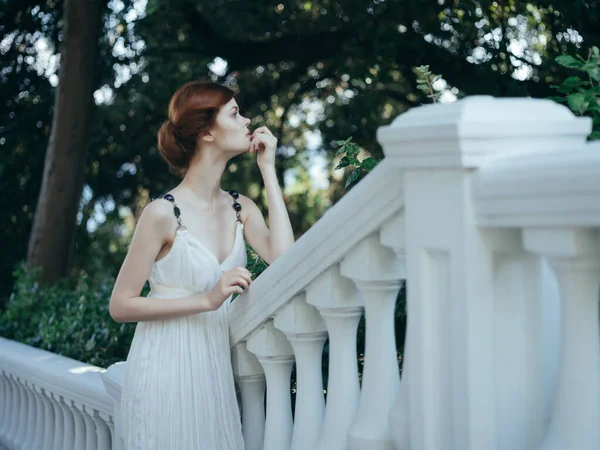 Красивая рыжая женщина в белом платье позирует в парковой мифологии — стоковое фото