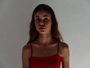 Kırmızı mayo giymiş güzel bir kadın şaşırmış görünüyor.