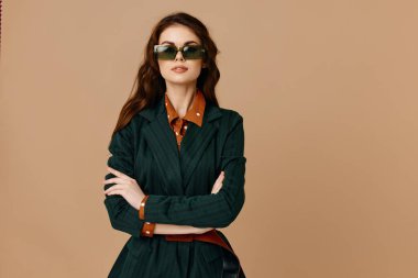 Güneş gözlüğü takan çekici bir kadın. Göz kamaştırıcı, kırpılmış bej bir arka plan.