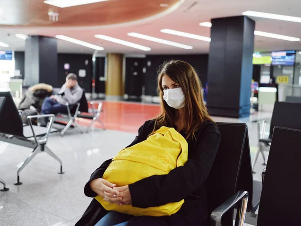 Mujer en máscara médica aeropuerto mochila amarilla esperando pasajero de vuelo — Foto de Stock