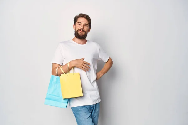 Hombre alegre en camiseta blanca con paquetes de compras emociones estilo de vida — Foto de Stock