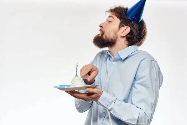 Férfi egy sapka a fejére lemez torta ünnep fény háttér — Stock Fotó