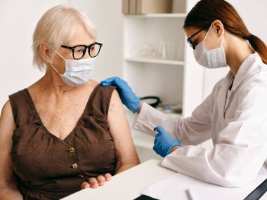 Hemşire Covid 'in pasaport iğnesinin yanındaki yaşlı kadın hastanede.