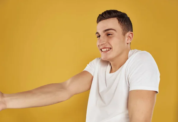 Man i vit t-shirt gester med händerna gul bakgrund — Stockfoto