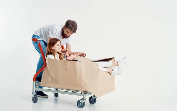 Mężczyzna toczy kobietę na wózku towarowym w pudełku — Zdjęcie stockowe