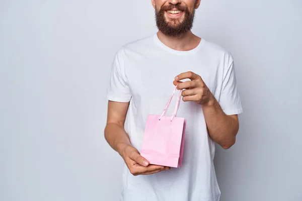Homem barbudo em t-shirt branca presente pacote rosa para estúdio mulher — Fotografia de Stock