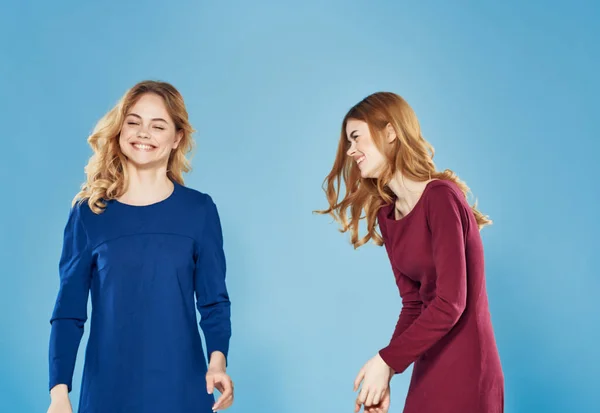 Två kvinnor i klänningar vänskap kommunikation mode blå bakgrund — Stockfoto