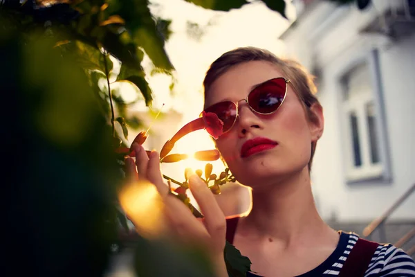 Kort hår kvinna bär solglasögon utomhus blommor dekoration — Stockfoto