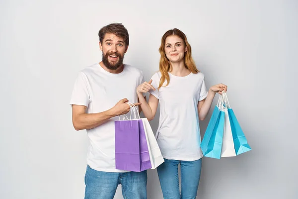 Jong paar in witte t-shirts met tassen in de hand winkelen plezier — Stockfoto