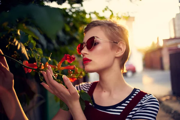 Kvinna med kort hår bär solglasögon utomhus blommor dekoration — Stockfoto