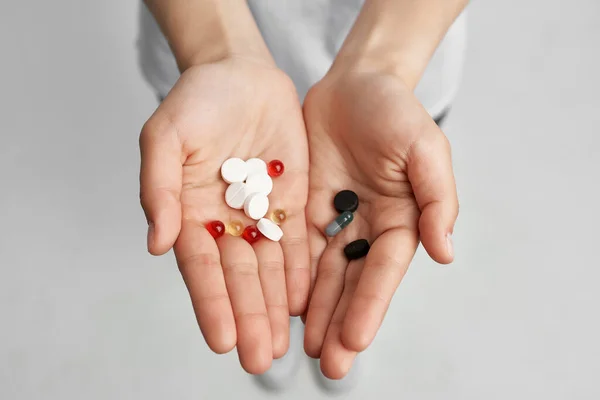 Женщина с таблетками в руках лечение проблем со здоровьем медицины — стоковое фото