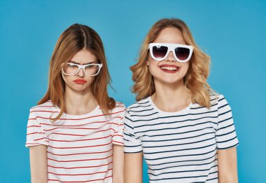 Neşeli kadınlar yazın moda tarzı mavi arka plana sarılır.