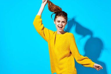 Sarı kazaklı kadın saçı mavi arka plan modasında.