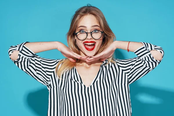 Mulher atraente vestindo óculos listrado camisa moda posando em fundo azul — Fotografia de Stock