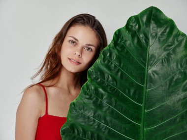 Kırmızı tişörtlü, yeşil palmiye yaprağı olan genç bir kadın. 