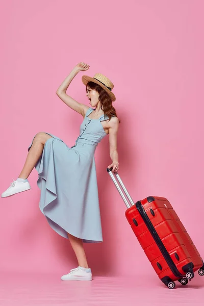 붉은 여행 가방을 들고 핑크 색 배경을 가진 파란색 옷을 입은 여자 — 스톡 사진