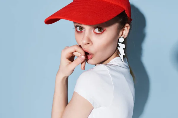 Emotionell kvinna i en röd mössa förvånad ser örhängen ljusa makeup mode närbild — Stockfoto